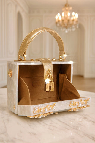 Luxury handbag with gold handle and embellishments on a marble surface