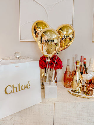Golden Balloons Sculpture Decor atop a marble coffee table from Anaïs Candle.