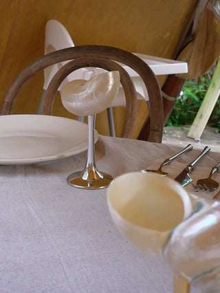 A Seashell Enchanté Cup™️ in silver in a tropical dining setting.
