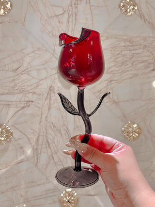 Rose for Rose Glass Cup in front of marble veined tiled wall and gold emblems.