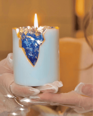 A woman holds the 18K Gold Blue Aquamarine Crystal Candle.