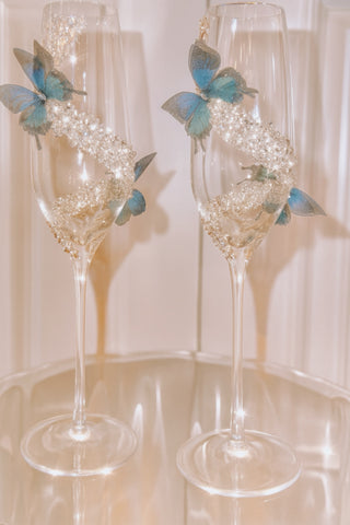 Butterfly Kisses Crystals Champagne Flute Set atop an acrylic side table.