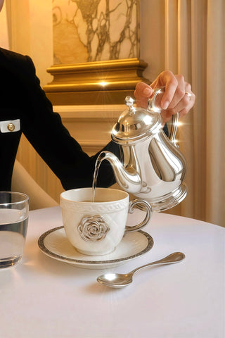 Pouring tea from a silver teapot into a Camellia Haute teacup in a 5-star hotel.