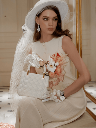 A woman seen using the Scarlett Handbag Resin Vase in Beige as a purse.