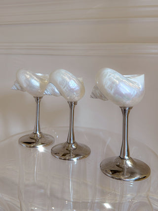 Three Seashell Enchanté Cups™️ in Silver atop an acrylic side table.