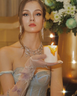 A model holding a lit 18K Gold Clear Quartz Candle – Clarity & Amplification.