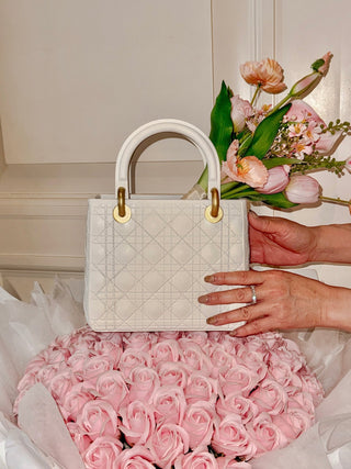 Scarlett Resin Handbag Vase in Beige atop a massive pink floral bouquet.