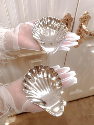 A woman holding two Celestial Seashell Plates in Stainless Steel.