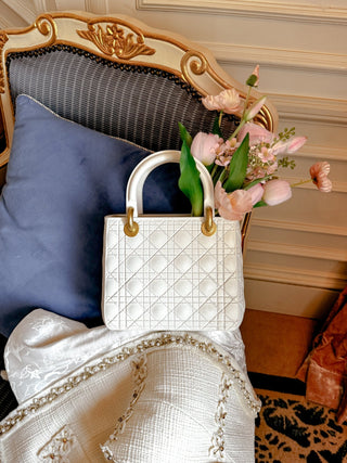 Scarlett Resin Handbag Vase perched on the armrest of a gilded chair.