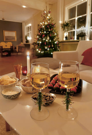 A Merry Christmas Wine Flute Set on a marble coffee table with holiday snacks and wine.