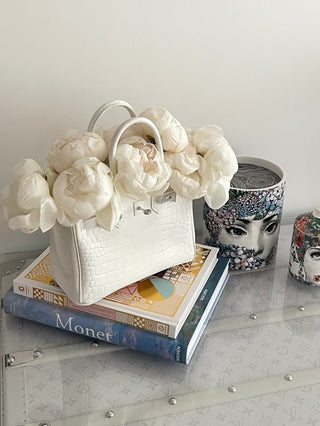 A Sandra Handbag Resin Vase filled with large white flowers.
