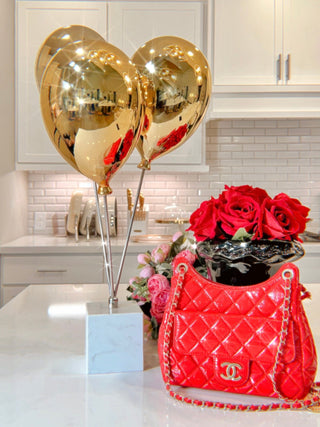 Golden Balloons Sculpture Decor next to flowers in a contemporary photo studio.