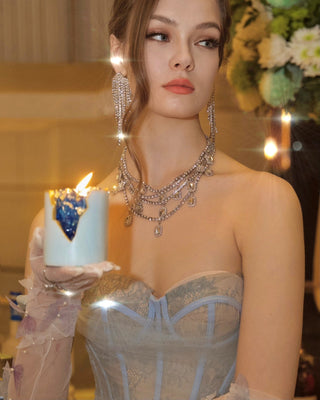 A model elegantly holds the 18K Gold Blue Aquamarine Crystal Candle.