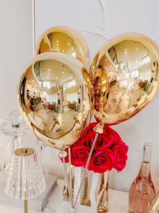 A close up view of the Golden Balloons Sculpture Decor atop a marble coffee table.