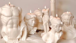 Seven Anais sculpture candles lit atop a table draped with luxurious silk.