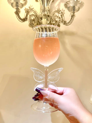 Dreamy Butterfly Champagne Flute Set of 2 held up to a wall sconce.