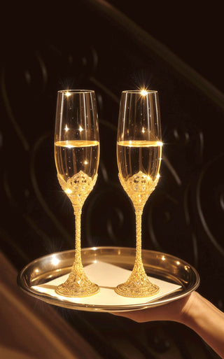 A Crowné Embossed Diamonds Champagne Flute Set of 2 in Gold served by a butler.