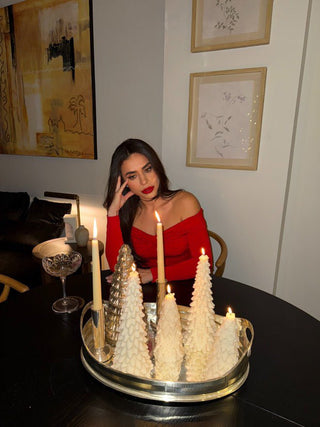 A woman posing with the Holiday Pine Tree Candle Set of 2.