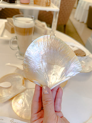 Woman holding a clamshell plate in a luxurious 'old-money' dining room.