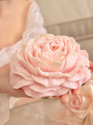 A model elegantly displays the Blooming Peony Candle - XXL in Pink and White.