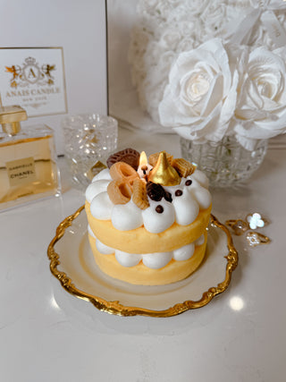 The Honey Gold Gâteau Cake Candle atop a marble coffee table.