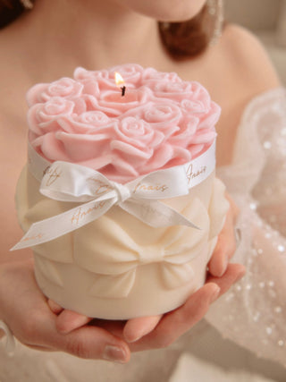 A woman delicately holds a Lavish Rose Bouquet Candle in Pink - XXL.