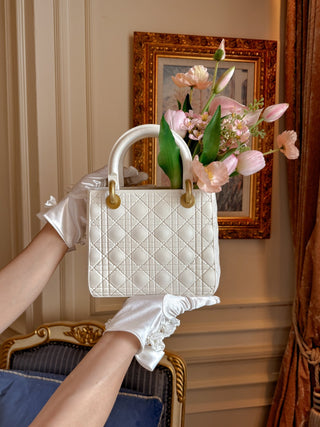 Scarlett Resin Handbag Vase held up in front of a gilded picture frame.