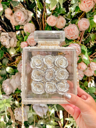 Everlasting Roses in Parfum Box - White in front of a stunning floral backdrop.