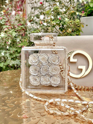 Everlasting Roses in Parfum Box - White placed atop a gold dining table.