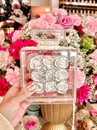 Everlasting Roses in Parfum Box - White surrounded by a large floral arrangement.