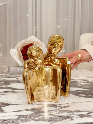 The lustrous 'Forever Us' Romantic Couple Statue - XXL Gold Electroplated is displayed with a bouquet of roses.
