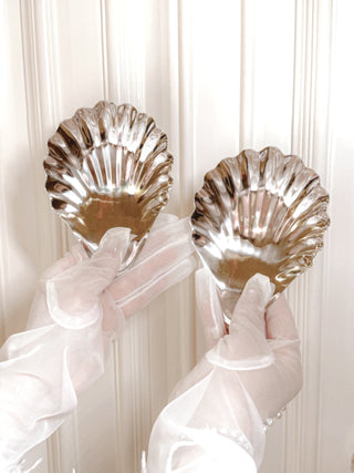 A model holding the Celestial Seashell Plate Set of 2 in a luxurious dining area.