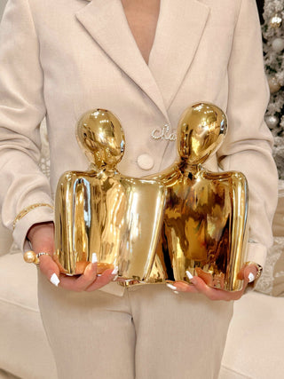 A woman holding the 'Forever Us' Romantic Couple Statue - XXL Gold Electroplated in each hand.