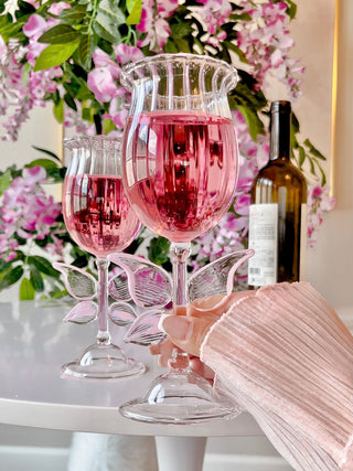 A woman hold her Dreamy Butterfly Champagne Flute Set of 2 filled with pink champagne.