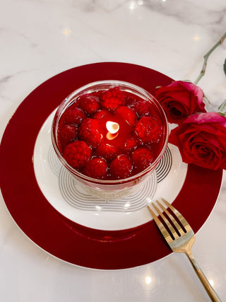 Raspberry Mousse Candle atop a beautiful, elegant red dinner plate.