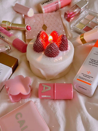 Anaïs Strawberry Shortcake Candle surrounded by pink makeup and skincare.