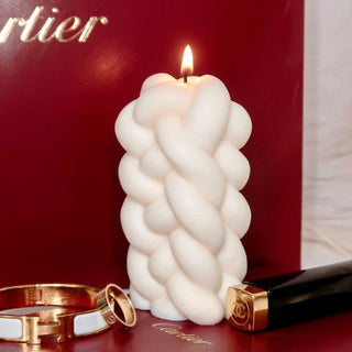 Knit Knot Candle nexet to luxurious jewelry and a red backdrop.