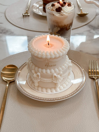 A Double Layer Creamy Vintage Cake on a dinner plate with a lit flame.
