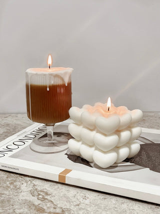 A lit “I Heart You” Candle next to a French Latte Candle.