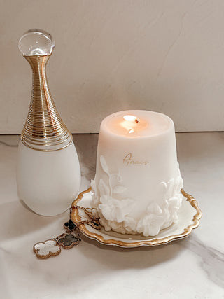 Embossed Floral Candle with a lit flame.