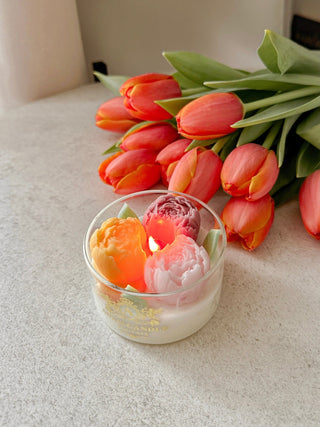 Peony Bouquet Candle surrounded by blooming tulips.
