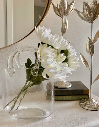 Olivia Glass Handbag Vase with white stemmed flowers atop a luxury white textured credenza.