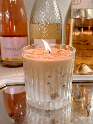 A lit Iced Caffè Candle in front of several bottles of beautiful wine.