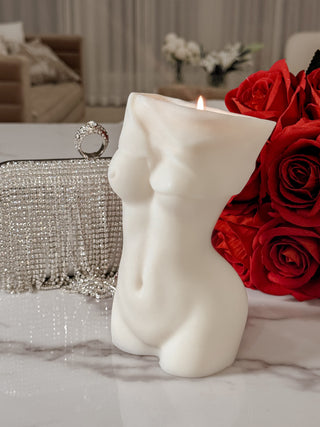 Anaïs Feminine Bust Candle atop a marble table and next to a red bouquet.