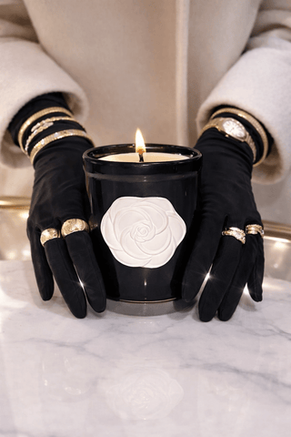 A woman displaying a new, lit Camellia Elegance Candle on a Calacatta marble table