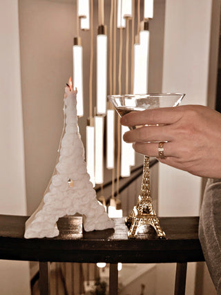 Rosy Eiffel Tower Candle in White, atop a banister and a backdrop of a modern LED chandelier.