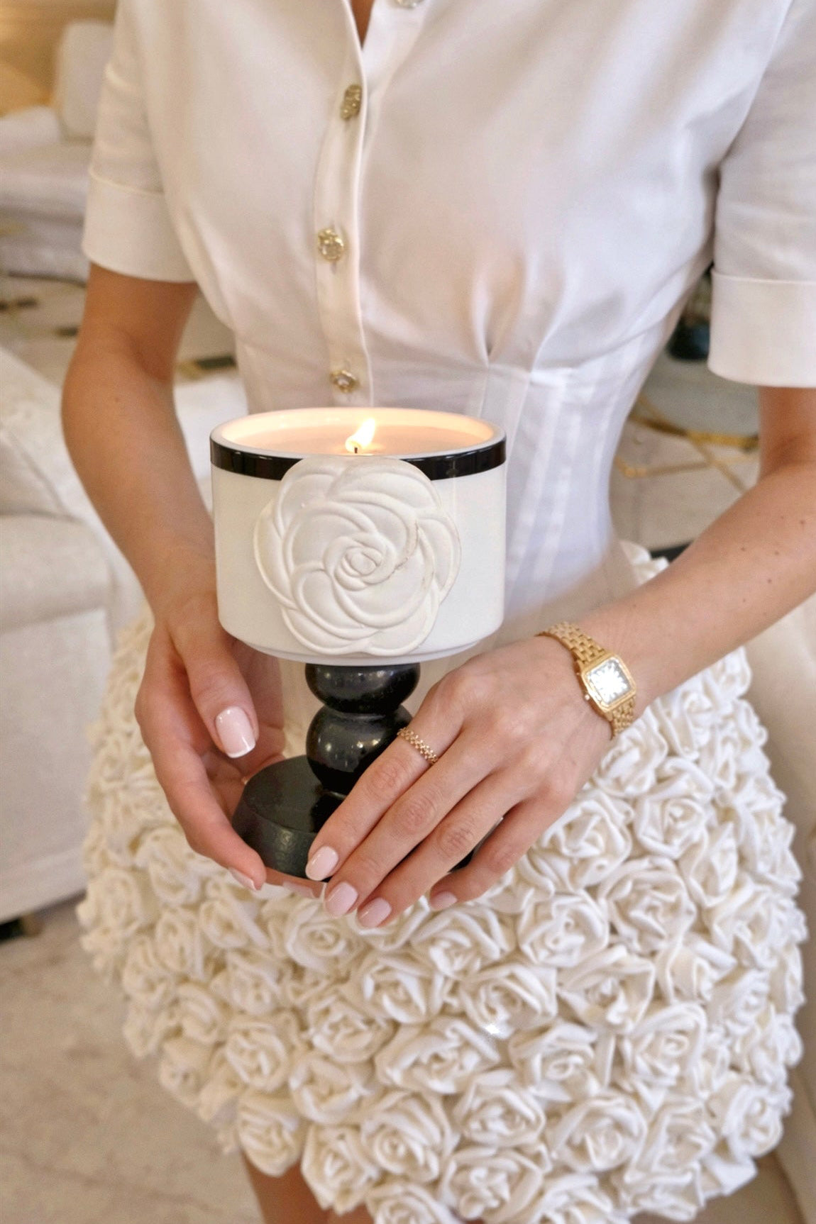 Woman holding the sculptural camellia candle in a refined interior