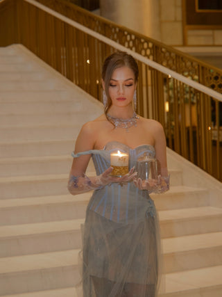 A woman holding a Majesté Dorée Gold Leaf Candle With Bell Cloche carefully.