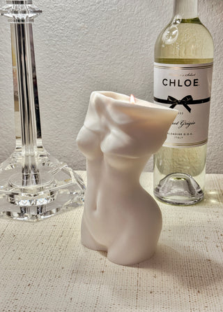 Anaïs Feminine Bust Candle and a bottle of wine, and lamp, atop a luxurious credenza.