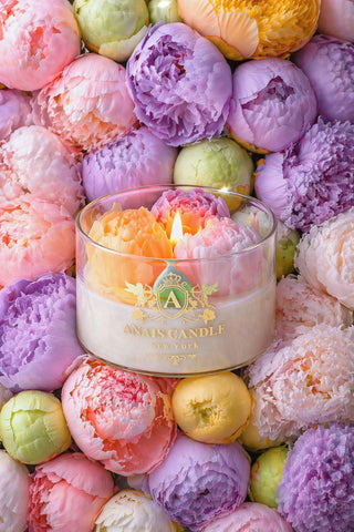 Peony Bouquet Candle surrounded by violet, orange, and yellow blooming peonies